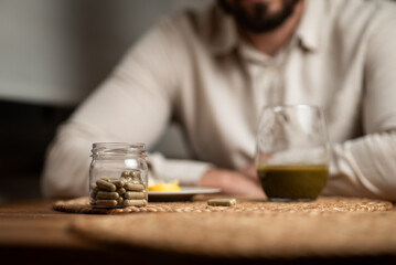 Kratom consumption concept:  male bearded hipster holds a ready to drink glass of green liquid, powdered kratom melted in hot water, kratom tea, close up photo, selective focus