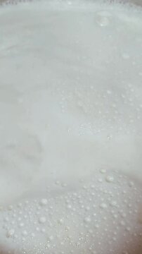 milk boils in a metal pan, vertical video