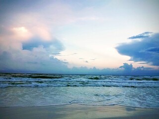 Obraz premium Serene beach scene with calm waves and fluffy clouds