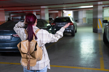 Surprised woman with a backpack in the basement parking lot, her car was stolen