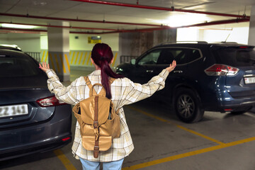 Surprised woman with a backpack in the basement parking lot, her car was stolen