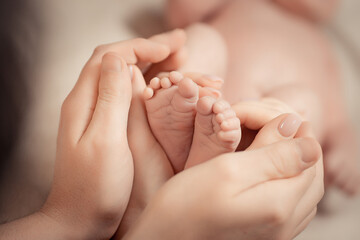 Parent holding in the hands feet of newborn baby. Soft brown toning