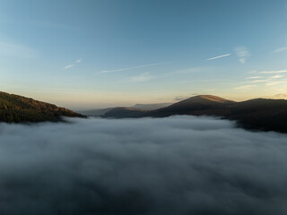 Breathtaking sunrise illuminating foggy valley in autumn mountains