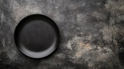 Black plate on a stone tabletop providing an empty area for a menu or recipe