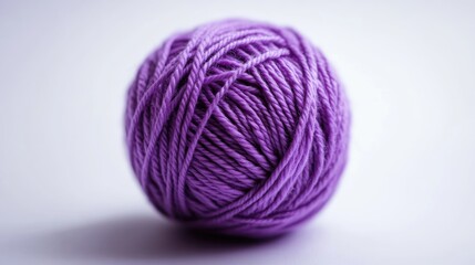 Close up view of a purple ball of yarn against a white background showcasing a knitting and crafting theme