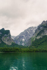 A stunning view of a lush green forest surrounded by towering mountain peaks. The serene landscape evokes a sense of peace and natural beauty, perfect for nature enthusiasts. Konigssee lake Bavaria