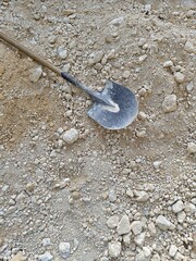 Close-up shot of a shovel resting on a pile of dirt at a construction site