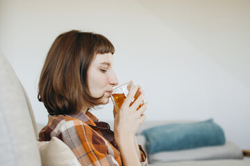 Serene Moment Of A Young Woman Enjoying A Warm Cup Of Herbal Tea, Finding Comfort And Relaxation In The Cozy Ambiance Of Her Home