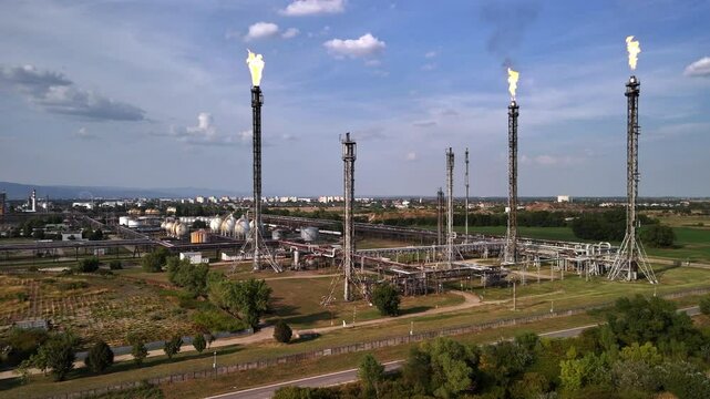 oil refinery field burners burning gases on a sunny day with blue sky background in Central Europe.