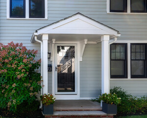 Front entry of a family home with gabled portico and storm door in Brighton, Massachusetts, USA
