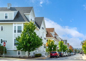 Serene residential street lined with multi-story family homes and trees in Brighton, Massachusetts,...