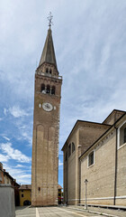 Portogruaor, Venice, Italy - June 26, 2024: Free-standing and leaning clock tower of Duomo di Sant'Andrea, the town Catholic church with against blue sky on Piazza Diuomo