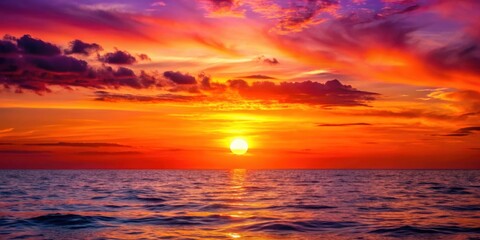 Obraz premium A vibrant and fiery sunset paints the sky above the ocean, casting a warm glow on the rippling waves.