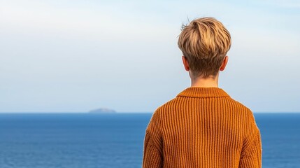 Fototapeta premium Self-love confidence and healing concept, A person with short, light hair gazes at the ocean, overlooking tranquil blue waters and a distant island under a bright sky.