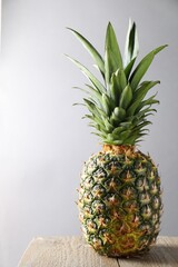 Fototapeta premium Fresh ripe pineapple on wooden table against light grey background