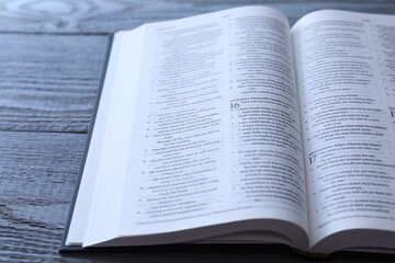 Open Holy Bible in English language on wooden table, closeup