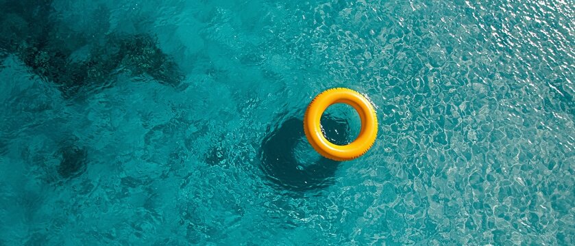 A vibrant yellow float ring sits serenely on crystal clear blue water, inviting relaxation and enjoyment in a refreshing summer getaway.
