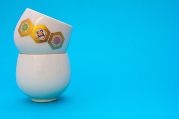 Floral Emblem Cups: Two ceramic cups, their floral emblems meticulously detailed, create a...