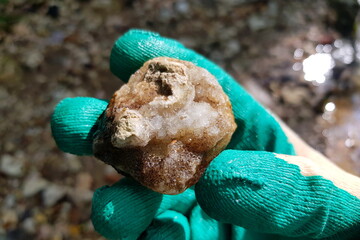 Stone with quartz druse found on river bank, rockhounding, field photo. Russia