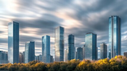 Obraz premium Skyline of skyscrapers under cloudy skies, buildings reflecting the sky in a soft blur, with trees at the base blending into the foreground, city banner,