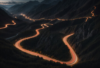 Long exposure shot of a winding mountain road at night with streaks of light trails from car headlights top view from drone