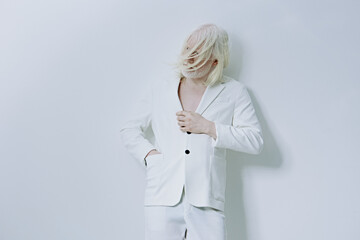 Elegant model wearing a white suit against a minimalist backdrop, showcasing a modern and stylish...