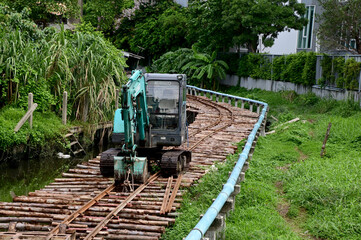 BANGKOK, THAILAND - December 8, 2024: A green excavator on a road of wooden logs for excavators to...