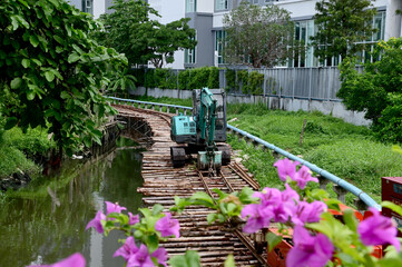 BANGKOK, THAILAND - December 8, 2024: A green excavator on a road of wooden logs for excavators to...