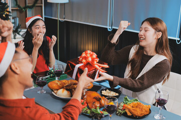 Group of young Asian man and women as friends having fun at a New Year's celebration, holding gift...