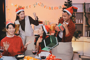 Group of young Asian man and women as friends having fun at a New Year's celebration, holding gift...