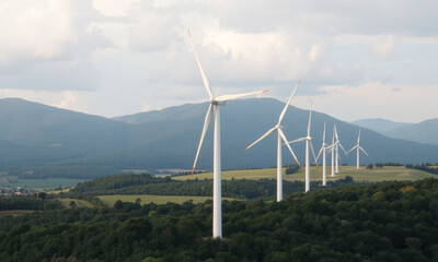 scenic view of wind turbines on hillside, surrounded by mountains and greenery, showcasing renewable energy in nature