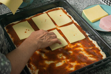 Person adding slices of buttery cheese to homemade pizza dough