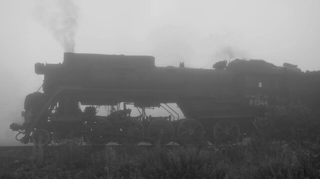 The old Soviet steam locomotive in a thick morning fog. Side view. Karelia