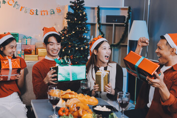 Group of young Asian man and women as friends having fun at a New Year's celebration, holding gift...