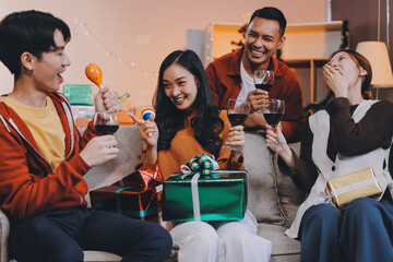 Group of young Asian man and women as friends having fun at a New Year's celebration, holding gift...