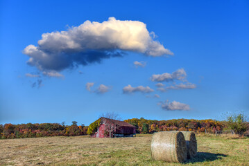Old rustic Red Barn on a farm during Autumn with fall colors and hay bales