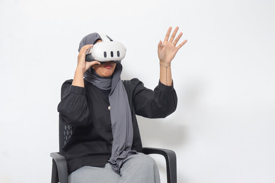 Portrait of Asian woman with hijab using virtual reality VR device, experiencing immersive technology. Isolated image on white background
