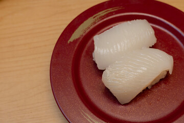 Ika Sushi or fresh squid, Japanese Restaurant that specializes in Japanese cuisine. serving on red plate.