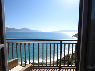 A serene balcony view showcasing the ocean and majestic mountains in the background.