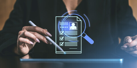 Woman using a stylus on a tablet with a holographic digital resume and magnifying glass icon...
