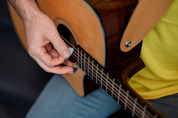 Guitarist on acoustic guitar playing melody. Close up musician instrument with pick in hand