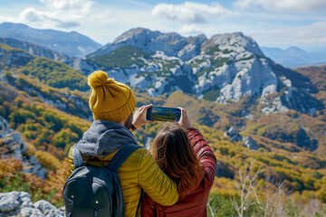 Fototapeta premium Man and woman take photo on the mountain. Beautiful view and cloudy landscape