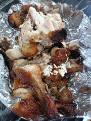 Roasted chicken with garlic and onions in aluminum foil, top view
