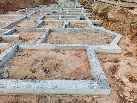 Construction of a modern building foundation with geometric shapes at a developing site under clear blue skies in urban area