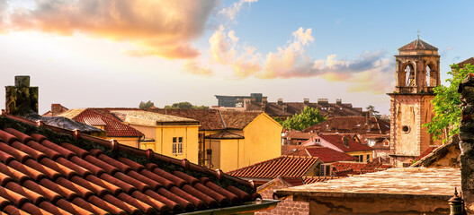 beautiful old city sunset landscape with ren and orange tile roofs of houses and nice cathedral church in traditional venetian style  with bell tower and chapel and evening sky on background