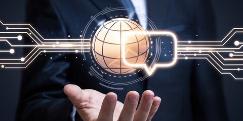 Businessman using global communication technology, symbolized by a world globe and speech bubble within a futuristic digital interface.