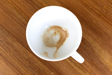 Heart Shape Coffee Stain Inside A White Mug On Wooden Table. Empty cofee cup with a heart on the...