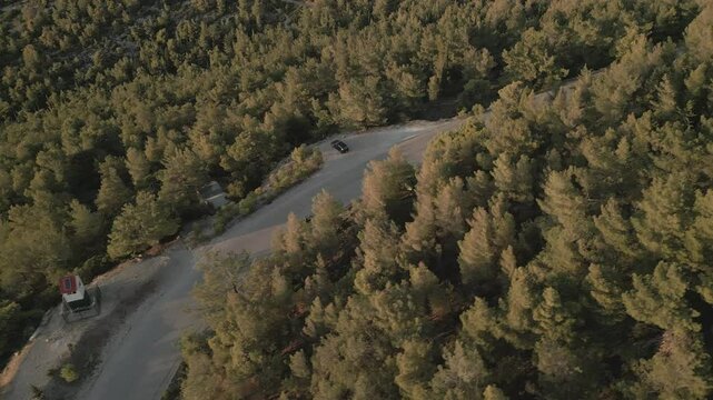 Motorbike in the pine forest on the mountain, aerial footage on sunset 