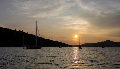 Serene Sunset Over a Tranquil Marina: Boats, Yachts, and Sailboats Reflect in Calm Waters Against a Majestic Mountain Backdrop.