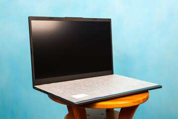 Laptop - portable computer open position on blue background.